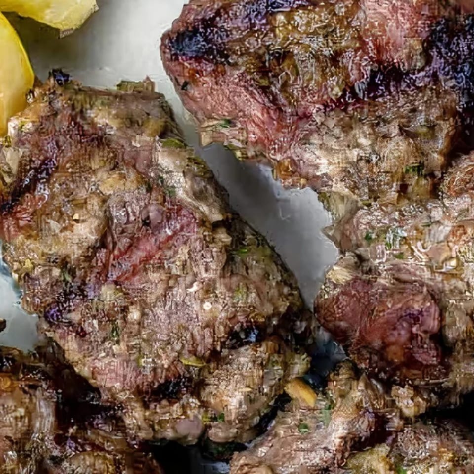 Close-up of grilled, seasoned meat pieces, possibly lamb or beef, from Albasha Express.