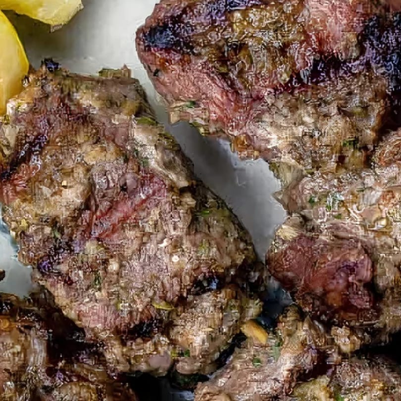 Close-up of grilled, seasoned meat pieces, possibly lamb or beef, from Albasha Express.